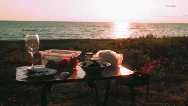 해변이나 바다에 바베큐 안경과 음식이있는 테이블 근처에 바베큐 그릴이 있습니다 — 비디오