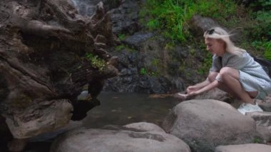 Kadının yakın plan portresi. Kadınların elleri Mirveti 'nin soğuk şelalesinin suyuna dokunuyor. Genç mutlu kadın ellerini uzatıyor, doğanın ve tatlı su şelalesinin tadını çıkarıyor, yolculuğun keyfini çıkarıyor..