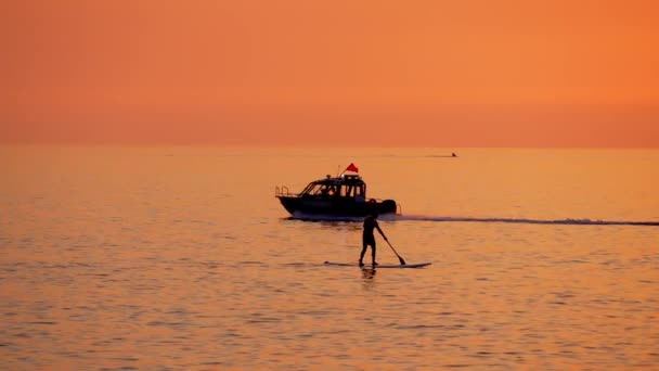 男は日没時に樹液に乗り 警察のボートは過去に浮いている 美しいオレンジ色の夕日が太陽を映し出しました 島の歴史について エキゾチックな観光 — ストック動画