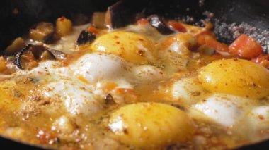 Tavada sebzeli yumurta. Ev yapımı Shakshuka. Yumurta sarısında baharat ve kırmızı biber haşlanıp sebzelerde kızartılmış. Yavaş çekim, taze sebze ve yumurtadan yapılan vejetaryen yiyecekler..