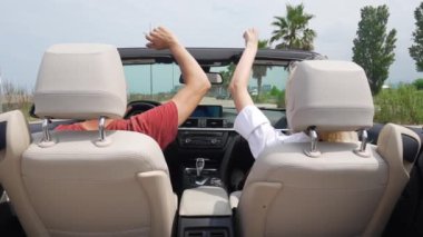 Üstü açık arabayla gezen bir çift. Gençler koltukta şarkı söyleyip dans ediyorlar. Birbirlerine aşık bir çift Auto Ride Concept Video. gezmek, araba kullanmak, açık çatılı bir arabada dans etmek. yavaş çekim