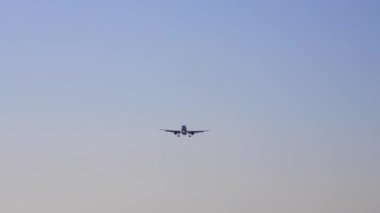Renkli mavi gökyüzüne iniş uçağı. Mavi gökyüzünde turuncu ve pembe bulutlarla uçan uçakların olduğu manzara. Yolcu uçağıyla seyahat etme geçmişi. Ticari Uçak. Özel Jet