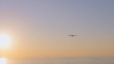 Renkli mavi günbatımı gökyüzünün arka planına güneşli bir uçak iniyor. Mavi gökyüzünde turuncu ile uçan uçakların manzarası. Yolcu uçağıyla seyahat etmenin geçmişi Özel Uçak Özel Jet