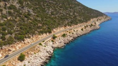 İHA 'dan sahil boyunca uzanan yol manzarası. Yazın arabayla seyahat etmek. Mavi deniz kıyısındaki dağ yolunun havadan görünüşü Karayolu, kayalıklar, deniz kıyıları