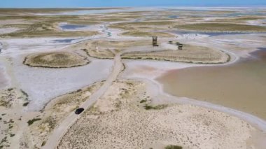 Türkiye 'deki ölü tuz gölü Tuz üzerinde giden arabanın insansız hava aracı görüntüsü. Manzara Ay 'daki ya da Mars' taki gibi, her şey tuzla kaplı. Burada fabrikada veya fabrikada yenebilir tuz çıkarılıp işleniyor..