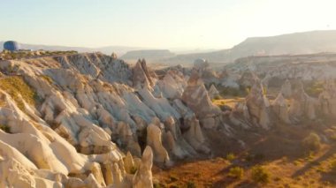 Nevsehir, Goreme, Kapadokya 'daki peri bacaları vadisinde uçan renkli sıcak hava balonları. Yeraltı şehri ve sıcak hava balonu turizminin nefes kesici panoramik drone görüntüsü.