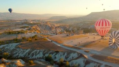 Goreme, Türkiye 5 Ağustos 2023: Nevsehir, Goreme, Kapadokya, Türkiye 'deki sihirli bacalar vadisinde uçan renkli balonlar. İnsansız hava aracından nefes kesici panoramik görüntü