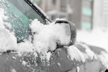 Çok fazla karla kaplı gri bir arabanın sağ yan aynasına yakın çekim. Kış, karlı hava, kötü hava