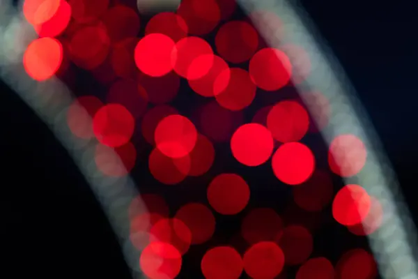 Abstract defocused background of bright red lights. Unfocused sparkling lights on the street. Bokeh of red lights