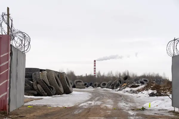 Mountain of old tires. dump of used wheels. Industrial landfill for processing of waste tires and rubber tires. Rubber Recycling. Tire dump. Background smoke and chimney. Vacuum frame.