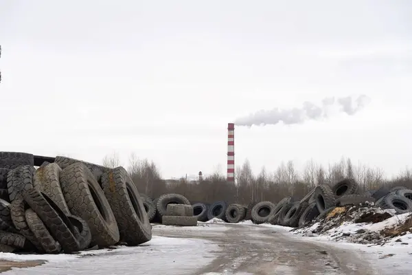 Mountain of old tires. dump of used wheels. Industrial landfill for processing of waste tires and rubber tires. Rubber Recycling. Tire dump. Background smoke and chimney. Vacuum frame.
