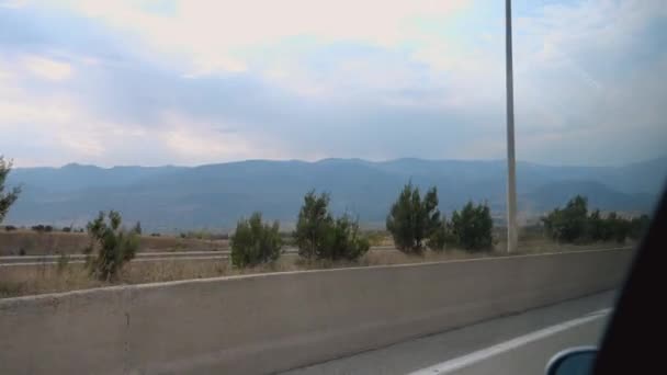 ジョージアを旅しながら車の横窓から見た青い空と山 車は道路を走り 遠くの山や農地の写真を撮りました — ストック動画