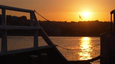 Gemi, yat ya da tekneden güverte ve korkuluklar. Güzel gün batımı ve okyanus manzarası, Türkiye 'de İstanbul' u bayrakla gören Boğaz. Gün batımında sakin denizde hareket eden yavaş çekim güvertesi teknesi.