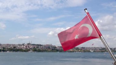 İstanbul, İstanbul 'daki İstanbul Boğazı' nda Türk bayrağı, güneşli bir arka planda güneşli bir günde rüzgarda dalgalanan dağlık kıyı dalgalarıyla denizde dalgalanan Türk ulusal bayrağında.