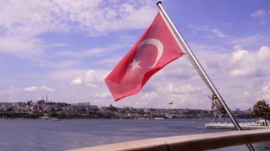 İstanbul, İstanbul 'daki İstanbul Boğazı' nda Türk bayrağı, güneşli bir arka planda güneşli bir günde rüzgarda dalgalanan dağlık kıyı dalgalarıyla denizde dalgalanan Türk ulusal bayrağında.