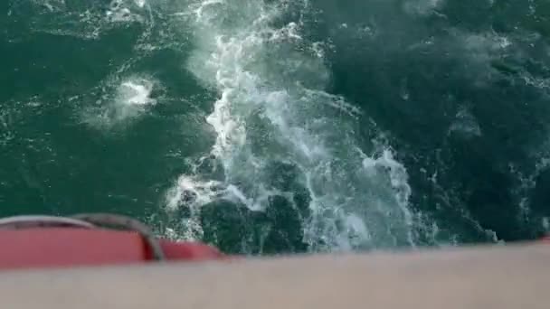 海上を航行する木造船のデッキと側面のトップビュー 船は深い青い海の泡立った白い波を通ってカットします 白い泡が付いている移動のプロペラのアウトボード モーターによって注入される白い泡 — ストック動画