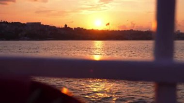 Gemi, yat ya da tekneden güverte ve korkuluklar. Güzel gün batımı ve okyanus manzarası, Türkiye 'de İstanbul' u bayrakla gören Boğaz. Gün batımında sakin denizde hareket eden yavaş çekim güvertesi teknesi.