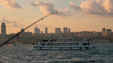İstanbul 'un arka planında balıkçılık yapan balıkçılar ve gün batımında geçen eğlence tekneleri, Altın Bölgede veya Boğaz' da şehrin güzel panoramik manzarası.