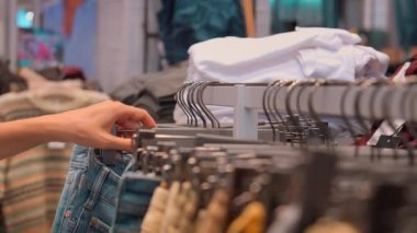 Kadın El Müşterisi Kadın Pantolonu Seçiyor ya da Kum Pantolonu Giysi Mağazasında Asılı. Moda ürünleri koleksiyonu mağazada satılıktır. Tekstil endüstrisi ve iş konsepti