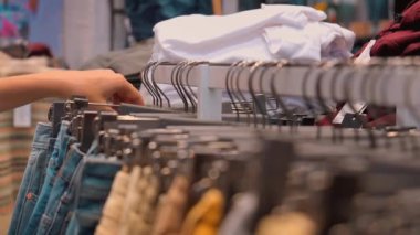 Kadın El Müşterisi Kadın Pantolonu Seçiyor ya da Kum Pantolonu Giysi Mağazasında Asılı. Moda ürünleri koleksiyonu mağazada satılıktır. Tekstil endüstrisi ve iş konsepti