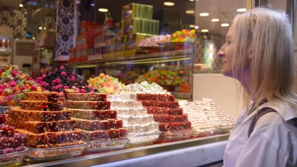 在东方糖果店里 女性游客通过商店玻璃或橱窗观看土耳其甜食时 会看到她们在东方食品市场上用甜点烘焙的柜台购买土耳其甜食 — 图库视频影像
