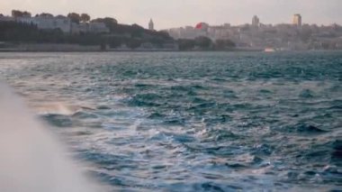 Güverte manzarası ve denizde giden ahşap tekne manzarası. Gemi derin mavi denizin köpüklü beyaz dalgalarını kesiyor. Beyaz köpüklü, hareket eden pervane motorundan çıkan beyaz köpük