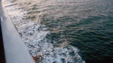 Güverte manzarası ve denizde giden ahşap tekne manzarası. Gemi derin mavi denizin köpüklü beyaz dalgalarını kesiyor. Beyaz köpüklü, hareket eden pervane motorundan çıkan beyaz köpük
