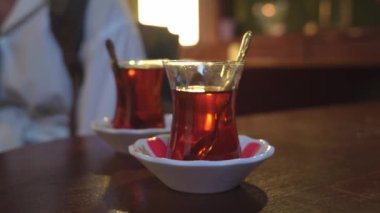 Türkiye 'de İstanbul' da geleneksel sıcak içecek konsepti olan çaydanlıktan iki fincan siyah Türk çayı döküldü. Ulusal içecek, güneş ışınlarıyla parlıyor. Amber rengi