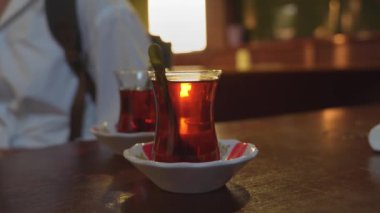 Türkiye 'de İstanbul' da geleneksel sıcak içecek konsepti olan çaydanlıktan iki fincan siyah Türk çayı döküldü. Ulusal içecek, güneş ışınlarıyla parlıyor. Amber rengi