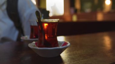 Türkiye 'de İstanbul' da geleneksel sıcak içecek konsepti olan çaydanlıktan iki fincan siyah Türk çayı döküldü. Ulusal içecek, güneş ışınlarıyla parlıyor. Amber rengi