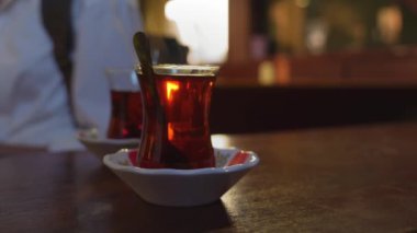 Türkiye 'de İstanbul' da geleneksel sıcak içecek konsepti olan çaydanlıktan iki fincan siyah Türk çayı döküldü. Ulusal içecek, güneş ışınlarıyla parlıyor. Amber rengi