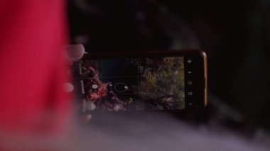 Turist akıllı telefonuyla muhteşem şelaleler çekiyor. Kadın turistlerin yakın planda çekilmiş görüntüleri. Akıllı telefondan yeşil doğa manzaralı şelale videoları çekiyor. Turist tatili