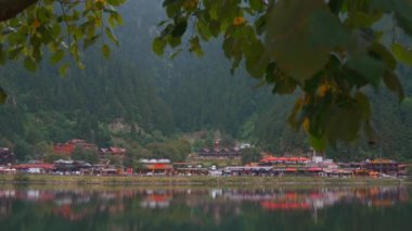 Trabzon, Türkiye - 2 Eylül 2023: Türkiye 'nin Trabzon kentindeki dağlarda Uzungol Gölü manzarası. Büyük dağ ormanı tepesi bulutlu bir günde köyde güzel göl ve camiyi gösteriyor..
