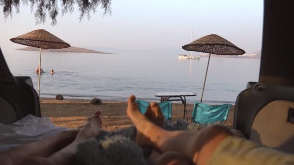 해변의 배경에 남성과 여자의 다리를 보여줍니다 공간은 해변에 테이블과 의자와 — 비디오