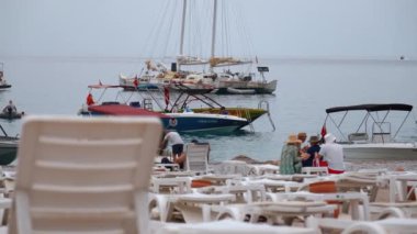 ZMIR, TURKEY - 1 Eylül 2023: Oludeniz plajında güneşlenen ve güneşlenen, güneşli bir günde resimli dağ manzarasına hayran olan bir grup insan.