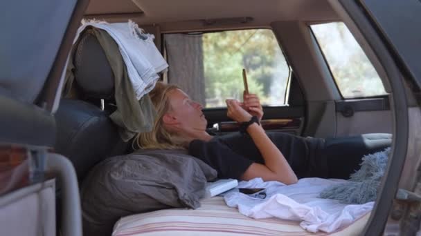 Молода Жінка Лежить Багажнику Машини Або Фургона Дивлячись Смартфон Читаючи — стокове відео