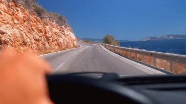 Arabanın ön camından asfalt yoldaki ilk şahıs görüntüsü. Şoförün elleri direksiyonu tutuyor. Doğa yollarında, dağlarda ve Türkiye 'nin güzel manzaralarında. Akdeniz kıyısı,