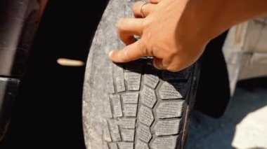 Adamın parmağı, eski, hasarlı ve siyah lastik izleri olan ön tekerleri işaret ediyor. Zamanı değiştir. Lastik İzi Sorunları ve Çözüm Konsepti. Camber ve ayak parmağı. tekerlekleri izlemek veya hizalamak