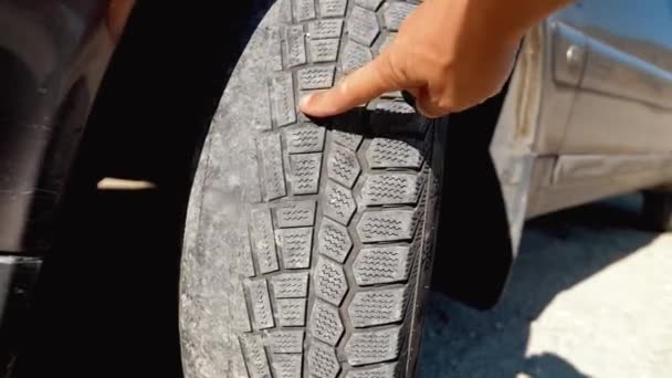フロントホイールの古い 損傷した 黒いタイヤのトレッドを指す人の手の指 時間を変える タイヤトレッドの問題と解決のコンセプト カンバーとつま先 ホイールの追跡または整列 — ストック動画