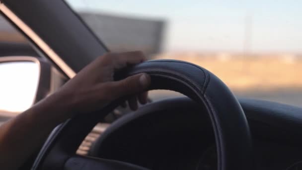 キャビンの中の車の側面の眺めを運転する男 車のステアリングホイールに横たわる運転手の手のクローズアップ 周囲や風景を見渡す — ストック動画