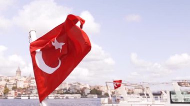 Türk bayrağı. Yakın plan. Bulutlu mavi gökyüzü ve arka planda İstanbul şehri. Türkiye 'nin ulusal bayrağı ağır çekimde sallanıyor.