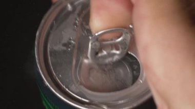 Eller, içinde soda olan alüminyum kutuyu açsın. Metal kavanozda su damlacıkları. Yiyecek içeceği. Erkek el yavaş çekimde siyah eğimli arka planda metal bira kutusu açıyor..
