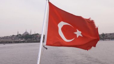 Türk bayrağı. Yakın plan. Bulutlu mavi gökyüzü ve arka planda İstanbul şehri. Türkiye 'nin ulusal bayrağı ağır çekimde sallanıyor.