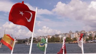 Türk bayrağı. Yakın plan. Bulutlu mavi gökyüzü ve arka planda İstanbul şehri. Türkiye 'nin ulusal bayrağı ağır çekimde sallanıyor.