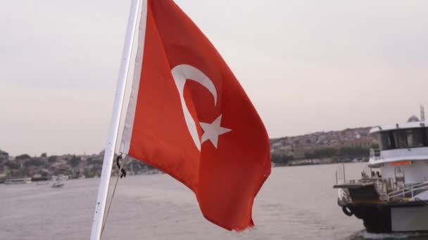 トルコ国旗 クローズアップ 背景に雲とイスタンブールの街の青空 トルコの国旗はゆっくりとした動きで風に揺れている — ストック動画