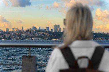 Beyaz gömlekli ve sırt çantalı genç bayan gezgin, İstanbul 'daki İstanbul Boğazı ve Avrupalı kesiminin muhteşem manzarasının keyfini çıkarıyor..