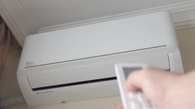 Odanın kliması duvarda asılı, uzaktan kumandalı bir erkek, ısıtma odasını açıyor. Uzaktan kumanda. Elektrikli ısıtma sistemi. Ochsenya ya da kış mevsiminde ısınma mevsimi.