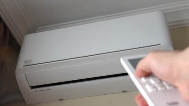 Odanın kliması duvarda asılı, uzaktan kumandalı bir erkek, ısıtma odasını açıyor. Uzaktan kumanda. Elektrikli ısıtma sistemi. Ochsenya ya da kış mevsiminde ısınma mevsimi.