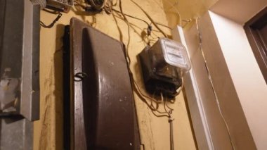 Tavandan sarkan çok eski fiş ve kablolar. Evin yenilenmesi ve eski düşük kaliteli elektrik kablolarının değiştirilmesi. Hatalı kablolama. Eski evin beyaz duvarından çıkan elektrik kabloları..