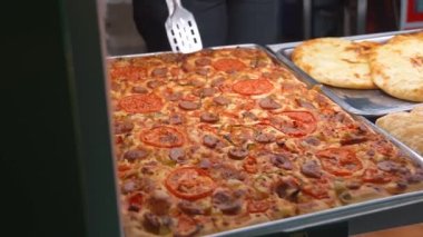 Akşamları sokakta lezzetli, kare pizza satmak. Sokak yemekleri, fast food, arka plan, ağır çekim, gece vakti hazır yemek. Satıcı, şehirdeki müşterilere pizza satıyor..